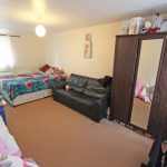 Cosy bedroom with bed, sofa, wardrobe, and soft toys.