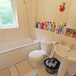 Clean bathroom with toiletries and laundry basket.
