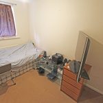 Small bedroom with bed, desk and TV.