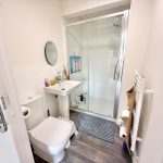 Modern bathroom with shower, toilet, and sink.