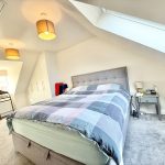 Modern attic bedroom with double bed and skylight.