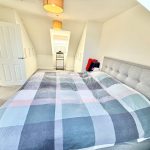 Spacious bedroom with checkered bedspread and modern decor.