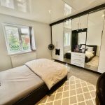 Modern bedroom with mirrored wardrobe and rug.