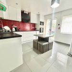 Modern kitchen with red tiles and dining area.