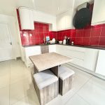 Modern kitchen with white cabinets and red tiles.