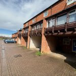 Terraced houses with car parking area in front.