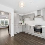 Modern grey kitchen with wooden floor and stainless appliances.