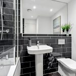 Modern bathroom with black tiles and white fixtures.