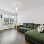 Modern living room with green sofa and large window.