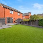 Neat garden with red brick house and patio.