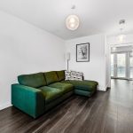 Modern living room with green sofa, white walls