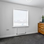 Minimalist bedroom with wooden dressers and carpet.