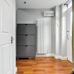 Modern hallway with wooden floor, radiator, and coat rack.