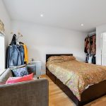 Bright bedroom with colourful bedding and open wardrobe.