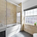 Modern bathroom with shower, sink, and window.