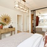 Modern bedroom with sunburst mirror decor.