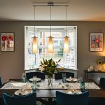 Modern dining room with floral decor and pendant lights.