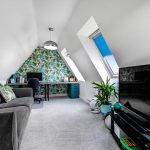 Modern loft room with office and TV setup.