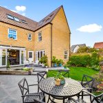 Sunny garden with patio seating and plants.