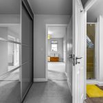 Modern hallway with open doors and yellow rug.