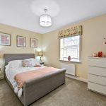 Cosy bedroom with grey bed and floral accents.
