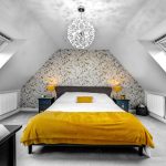 Cosy attic bedroom with floral wallpaper and skylights.