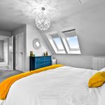 Bright bedroom with skylights and blue dresser.
