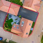 Aerial view of houses with cars and garden.