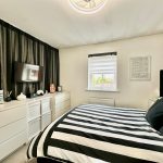 Modern bedroom with striped bedspread and TV.