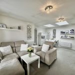 Modern living room with beige sofas and skylights.