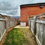 Narrow garden path with wooden fences and shed.