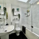 Modern bathroom with white fixtures and greenery.