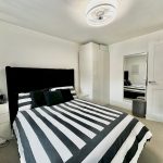 Modern bedroom with striped bedding and large mirror.