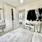 Spacious tidy bedroom with modern white furniture
