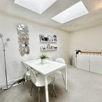 Modern white dining room with skylights and decor.