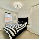 Modern bedroom with striped bedding and white furniture.