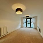 Empty room with carpet, curtains, radiators, and lights.