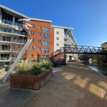Modern canal-side apartments with sculpture and footbridge