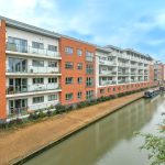 Modern canal-side apartments with narrowboats docked.