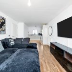 Modern living room with black sofa and abstract art.