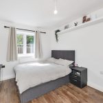 Modern bedroom with double bed and hardwood floor.