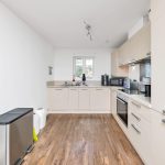 Modern kitchen with wooden floor and white cabinets.