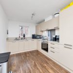 Modern kitchen with beige cabinets and wooden floor.
