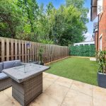 Modern patio with seating and artificial grass lawn.