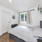 Cosy bedroom with grey bed and window view.