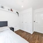 Minimalist bedroom with white walls and wooden floor.