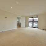 Spacious living room with carpet and large windows.