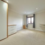 Spacious beige room with wardrobe and window.