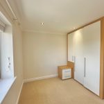 Modern bedroom with fitted wardrobe and window view.