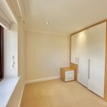 Bright room with large wardrobe and window view.